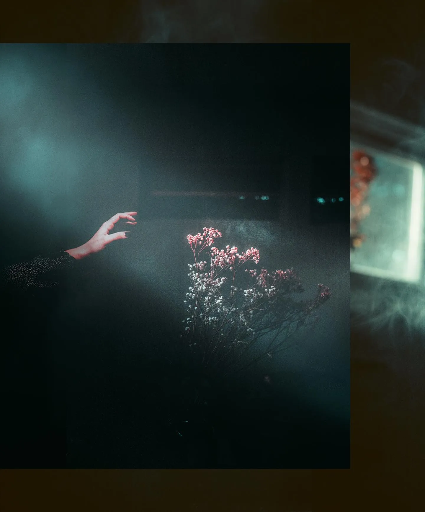 A hand reaching up into a cloud of glowing sparks in near-darkness, gold and bronze tones.
