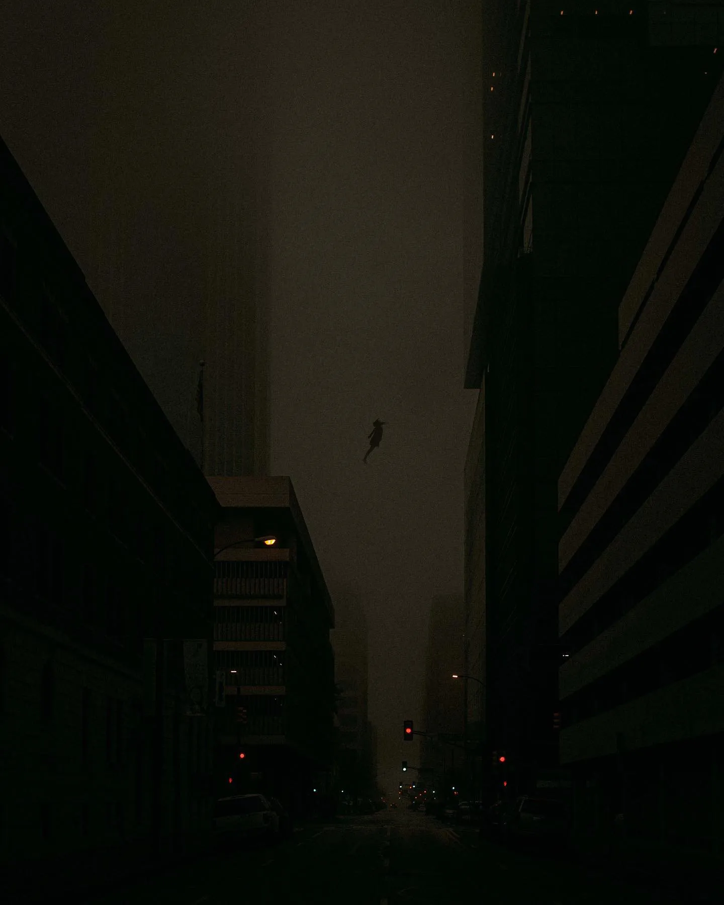 A very dark interior or alley, near-black, with faint light at the far end.