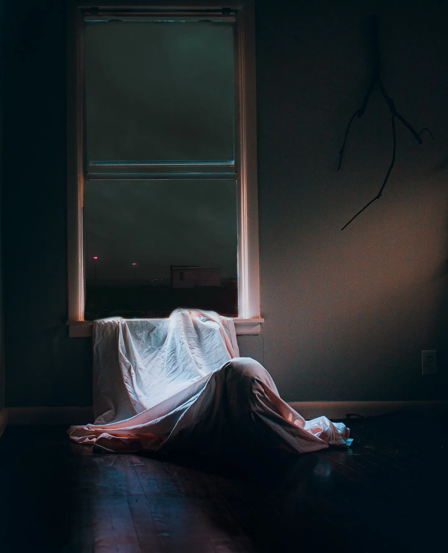 A white cloth form on a windowsill in a dark room lit by one bright window.